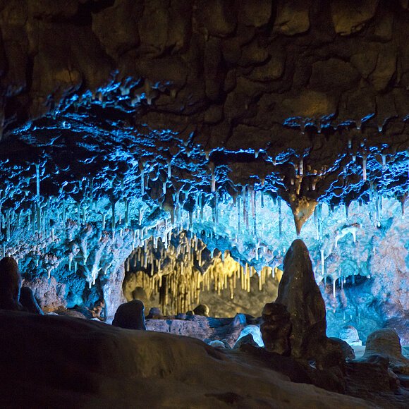 Die Tropfsteinhöhle mit ihren Stalagniten blau ausbeleuchtet.